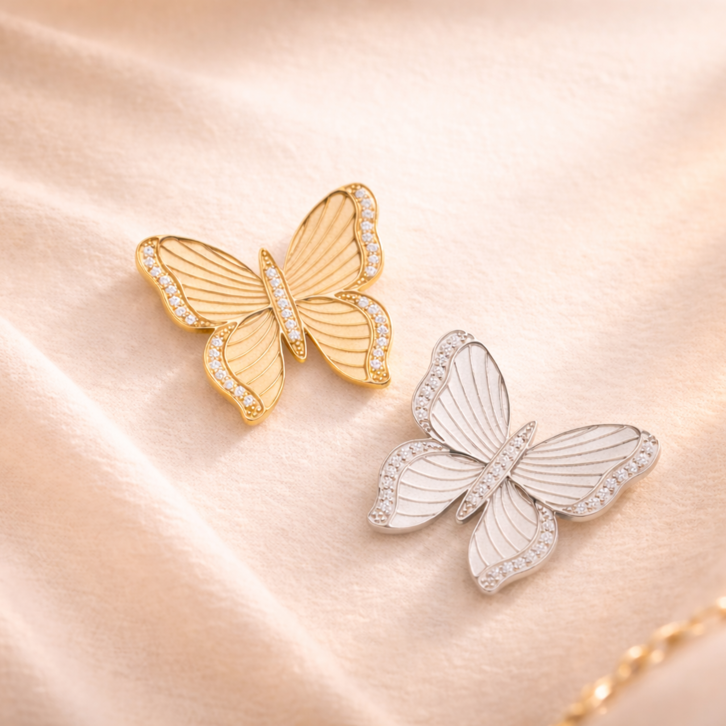 Gold and silver butterfly-shaped jewelry pieces on a soft pink background