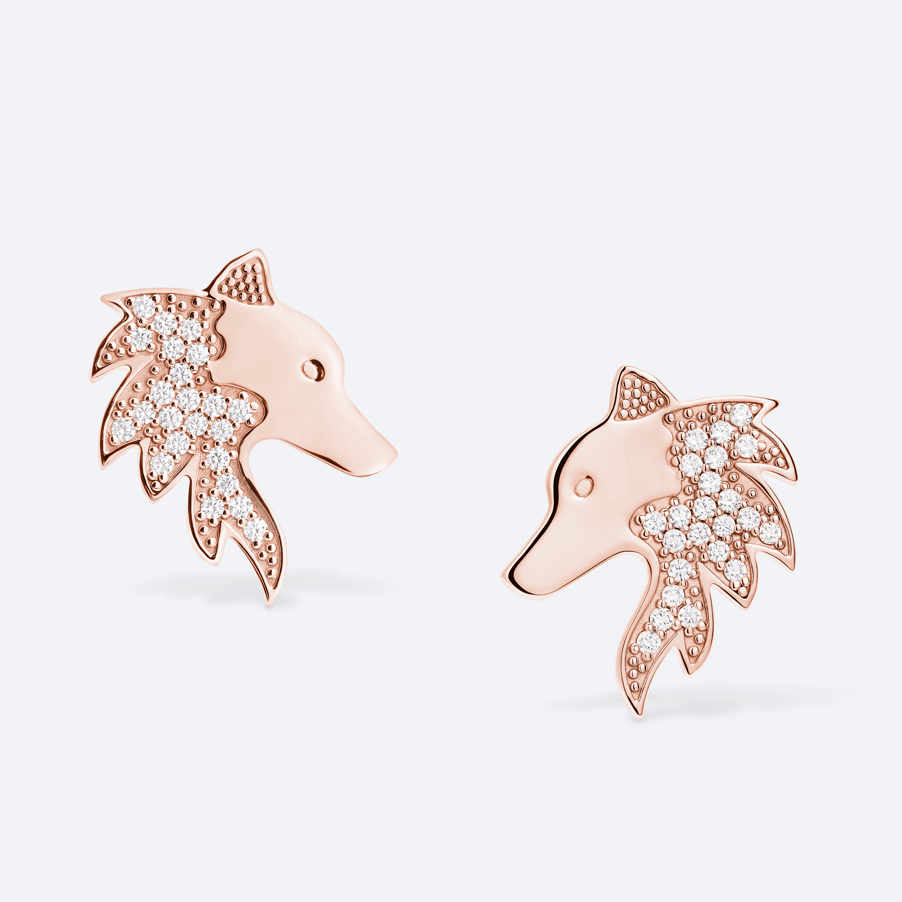 Rose gold dolphin-shaped earrings with diamond accents on a light gray background