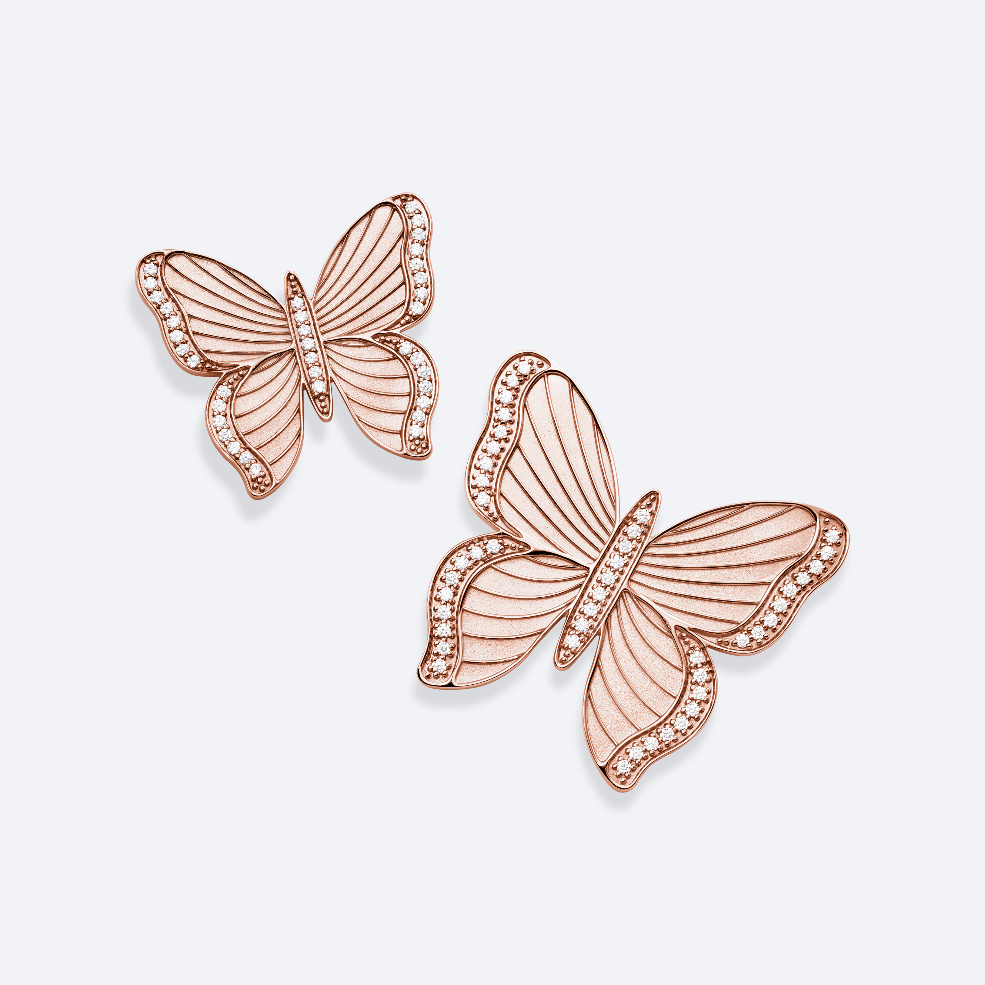 Rose gold butterfly earrings on a light gray background