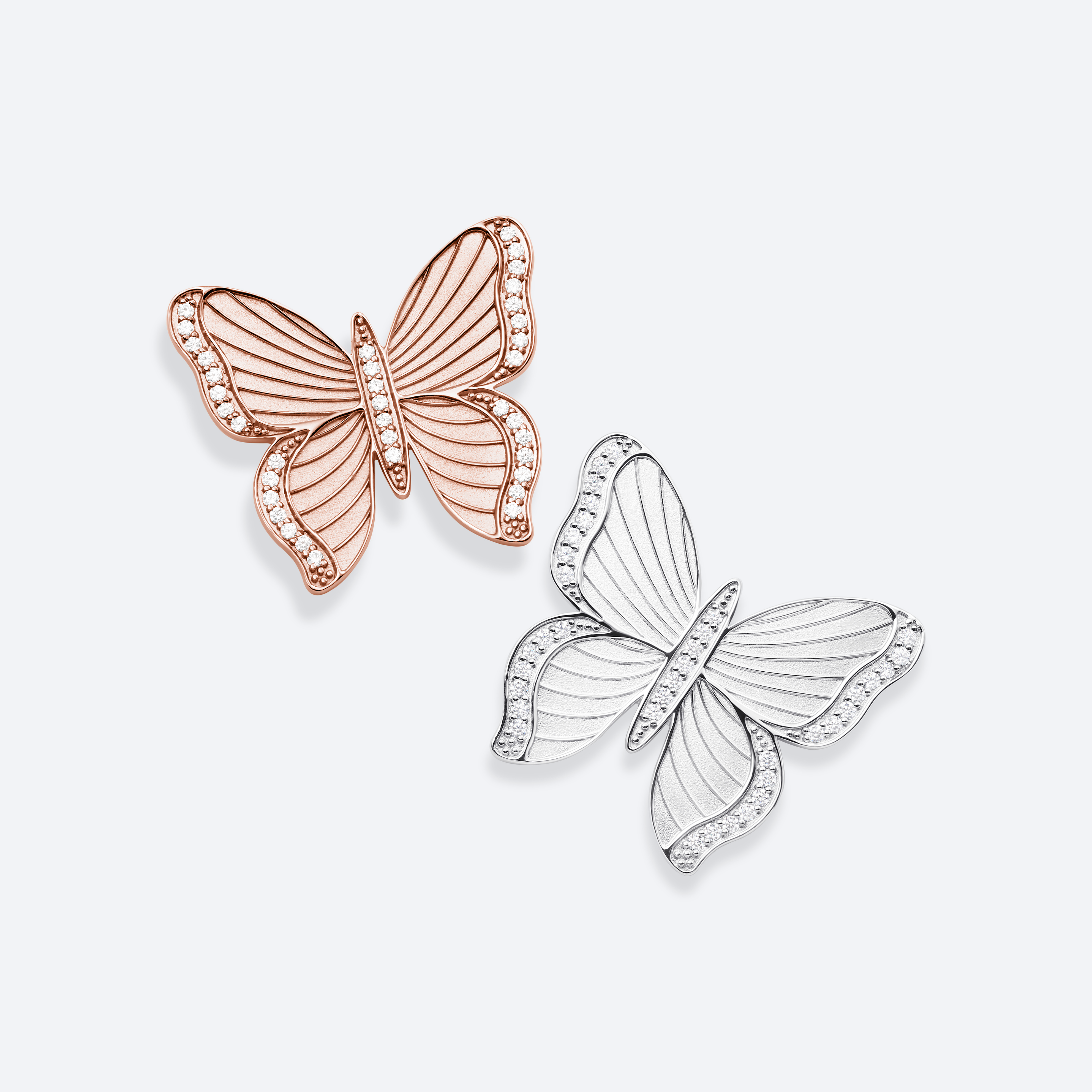 Butterfly-shaped earrings in rose gold and silver on a light gray background