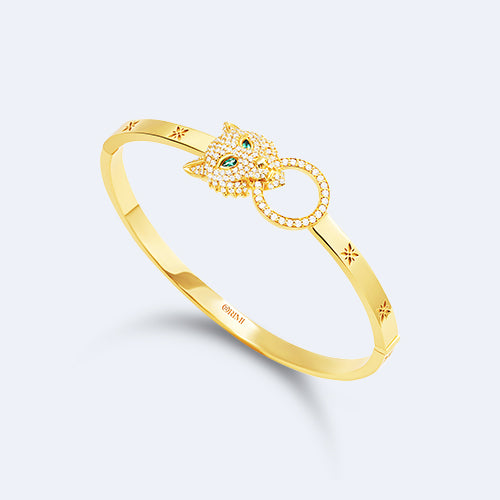 Gold bracelet with a decorative clasp on a light gray background