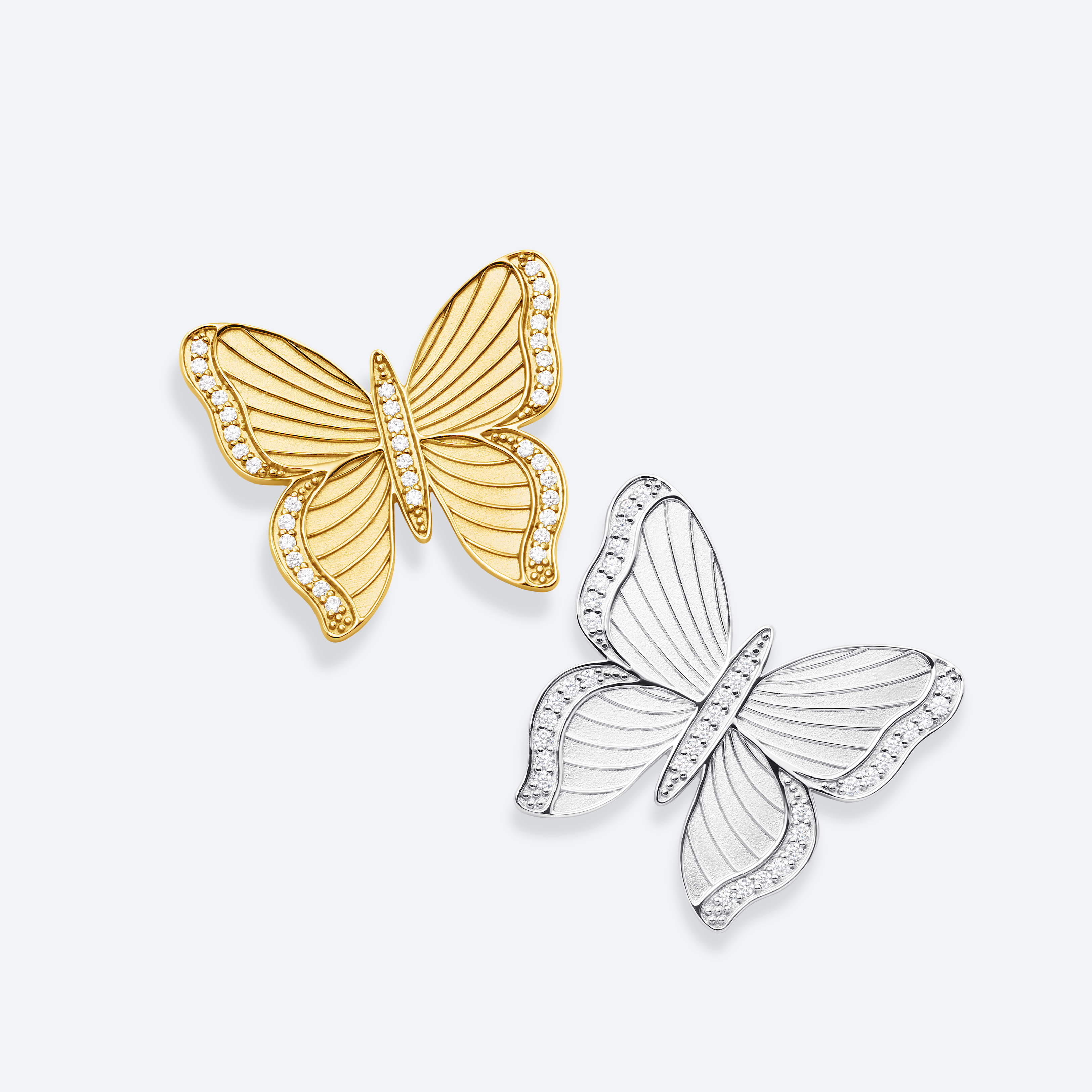 Gold and silver butterfly-shaped earrings on a light gray background